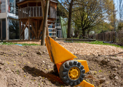 Dreckhaufen mit Sandspielfahrzeug im Spielgarten von InKiTa Kindergarten