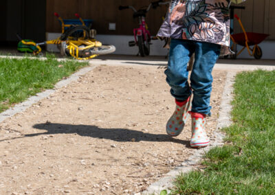 laufendes Kind mit Gummistiefeln im Garten im Haus für Kinder