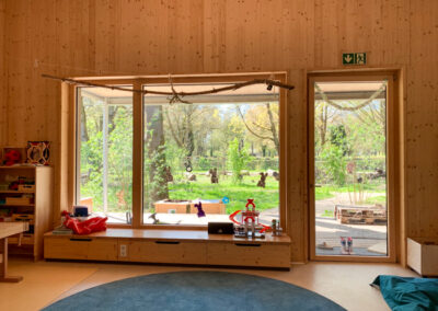 großes Fenster mit Blick in den Naturgarten im Haus für Kinder