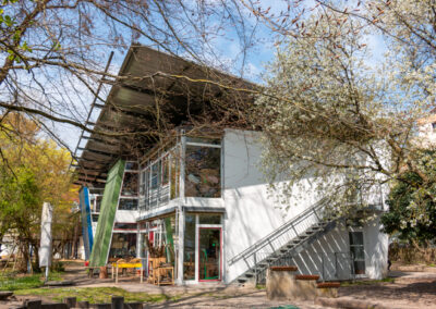 Blick auf das Gebäude von InKiTa Kindergarten mit blühenden Bäumen